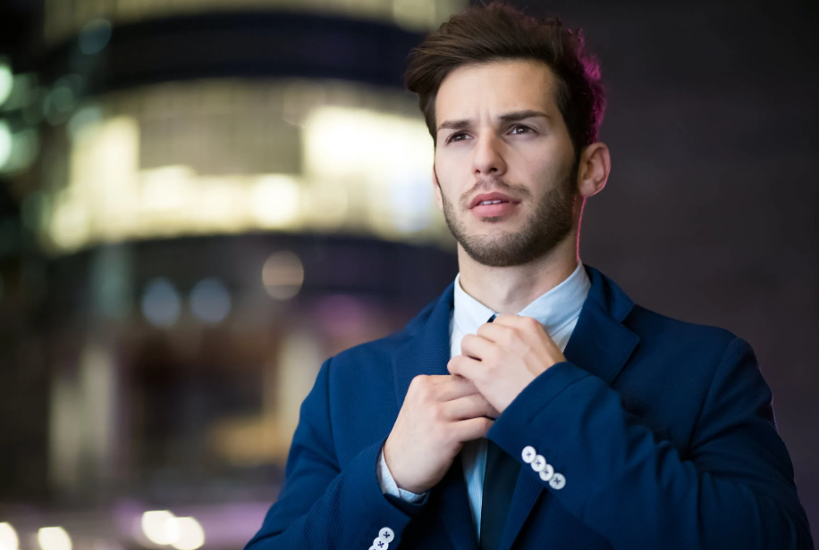 man in blue suit fixing his tie